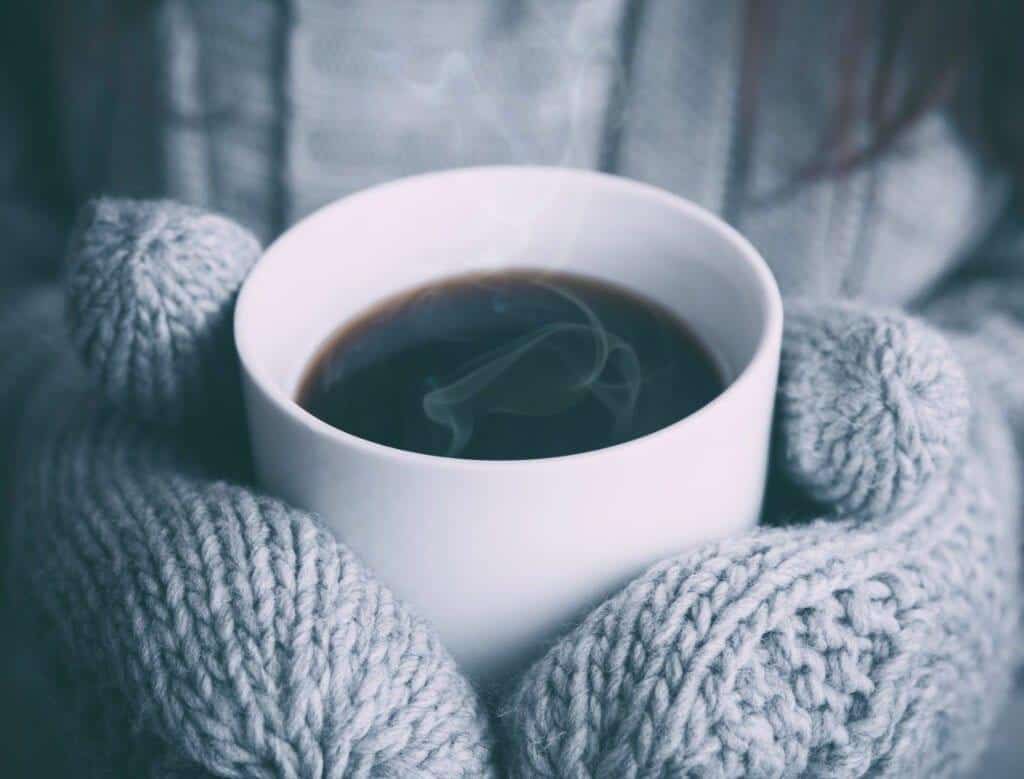 Person holding a cup of hot coffee in their hands
